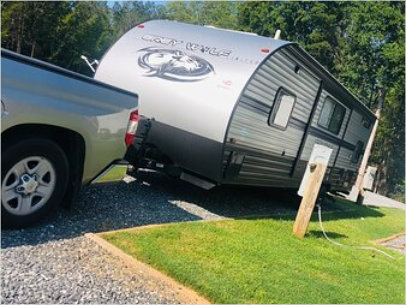 A camper trailer attached to a truck parked at one of the Maple Ridge RV Park sites