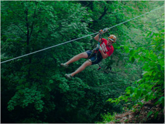 A man is zip-lining through the trees