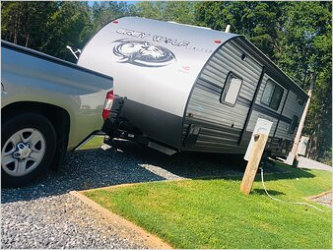 A camper trailer attached to a truck parked at one of the Maple Ridge RV Park sites